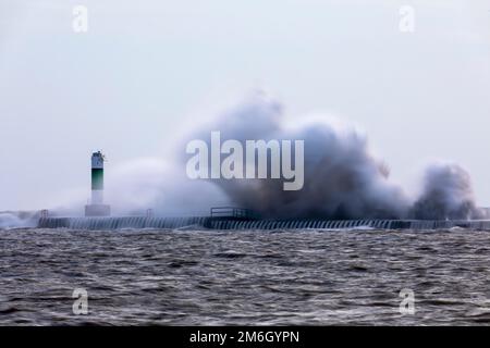 Le onde si schiantano su un molo con un faro sul lago Michigan Foto Stock