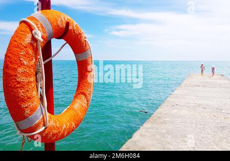 Primo piano di Lifebuoy sul molo sullo sfondo del mare Foto Stock