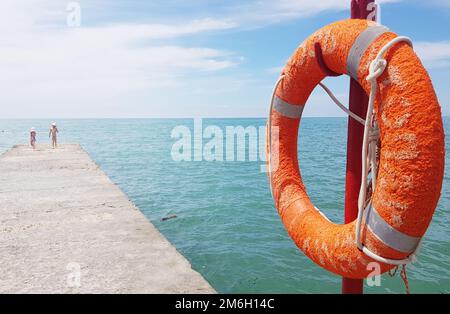 Primo piano di Lifebuoy sul molo sullo sfondo del mare Foto Stock