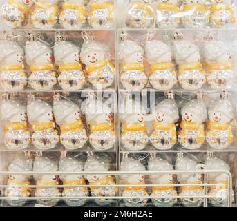 Un sacco di luccicanti pupazzi di neve sono allineati in fila in una vetrina. Natale decorazione pupazzo di neve nel pacchetto. Foto Stock