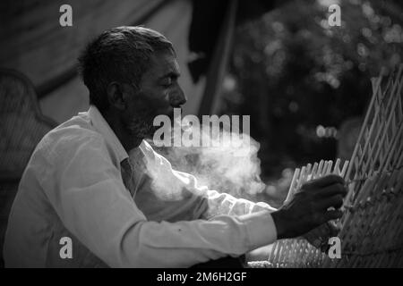 Vadodara, Gujarat - Novembre 19th 2022: Uomo indiano anziano primo piano faccia con pelle rugosa e capelli grigi buona e bella faccia fumo Foto Stock