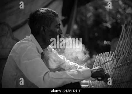 Vadodara, Gujarat - Novembre 19th 2022: Uomo indiano anziano primo piano faccia con pelle rugosa e capelli grigi buona e bella faccia fumo Foto Stock