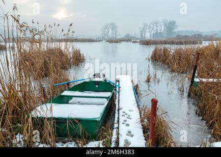 Una barca al molo su un lago ghiacciato Foto Stock