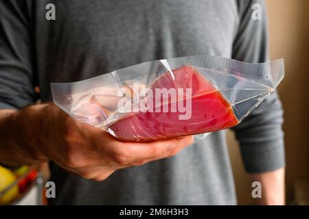 Tiene in mano un pezzo di tonno in una confezione Foto Stock