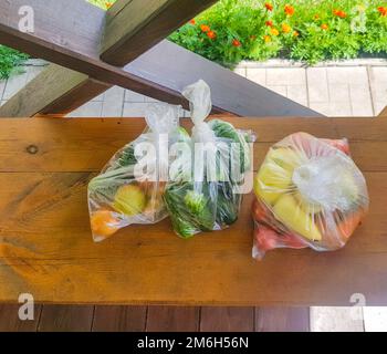 Cetrioli freschi, pomodori, peperoni dolci in sacchetto di plastica, raccolto dal giardino di casa, per la vendita al mercato agricolo. Salute Foto Stock