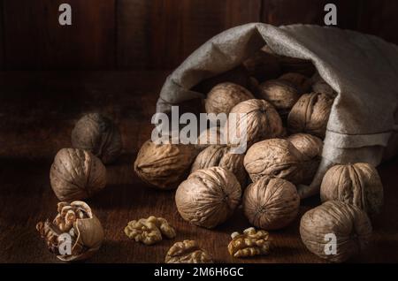 Borsa con noci e nocciole su fondo di legno scuro Foto Stock