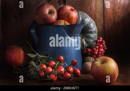 Mele in una brocca da giardino su sfondo di legno scuro in stile rustico Foto Stock