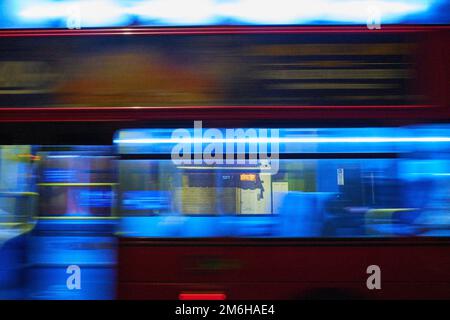 L'interno luminoso di un autobus londinese passa in una sfocatura mentre la strada che si trova dietro viene vista attraverso le finestre Foto Stock