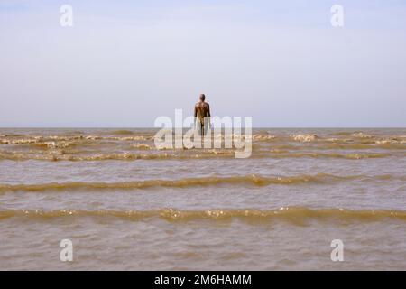 La marea si scontra con la scultura di Anthony Gormley, un altro luogo su Crosby Beach Foto Stock