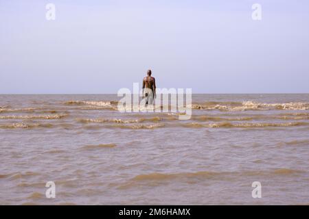 La marea si scontra con la scultura di Anthony Gormley, un altro luogo su Crosby Beach Foto Stock