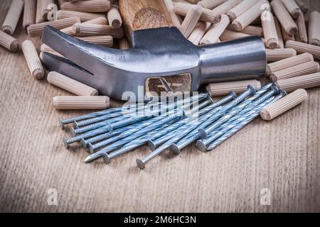 Tasselli per legno chiodi martello da artiglio su fondo in legno. Foto Stock