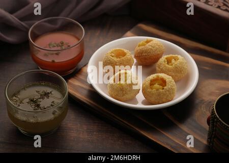 Snack indiani Gol Gappe o Pani Puri o Puchka Water Balls in un piatto bianco con acqua aromatizzata Foto Stock