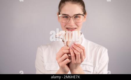 Medico estetista che tiene gouache raschietto e rullo. Foto Stock