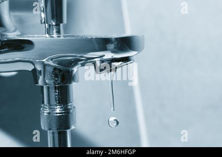 Rubinetto cromato con gocce d'acqua in caduta da vicino Foto Stock