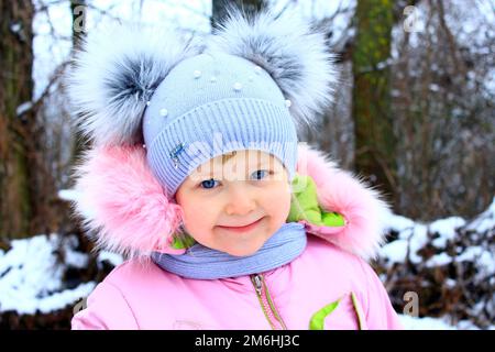 Ritratto di bambino sorridente in divertente berretto invernale con due orecchie divertenti Foto Stock