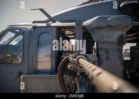 Dominic Brinker, 66th Rescue Squadron (RQS), istruttore aviatore di missioni speciali, ispeziona una mini pistola durante i controlli pre-volo alla base dell'aeronautica militare di Nellis, Nevada, 28 aprile 2022. Il 66 RQS impiega tatticamente l'elicottero HH-60G e il suo equipaggio in ambienti ostili per recuperare l'equipaggio aereo abbattuto e il personale isolato durante il giorno, la notte o le condizioni atmosferiche marginali nello spazio aereo contestato, impiegando competenze come impiego di armi, operazioni di bordo e rifornimento aereo. Foto Stock