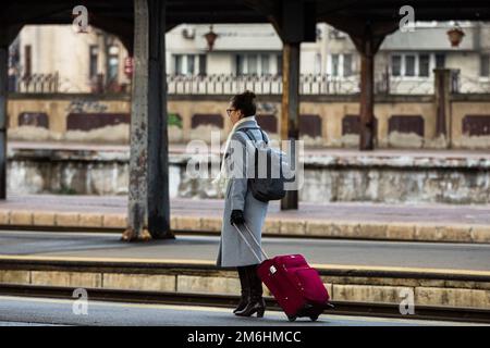 Turisti che tirano i bagagli. Pendolari a piedi alla stazione ferroviaria piattaforma a Bucarest, Romania, 2022 Foto Stock