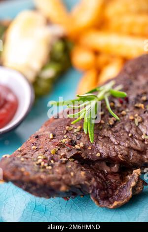 Rosmarino su una bistecca con patatine fritte Foto Stock