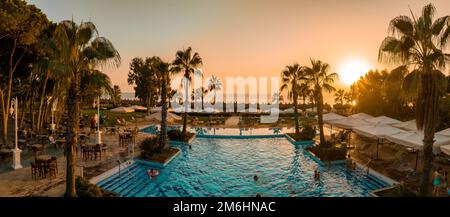 Lussuoso resort sulla spiaggia con piscina e sedie a sdraio e palme. Foto Stock