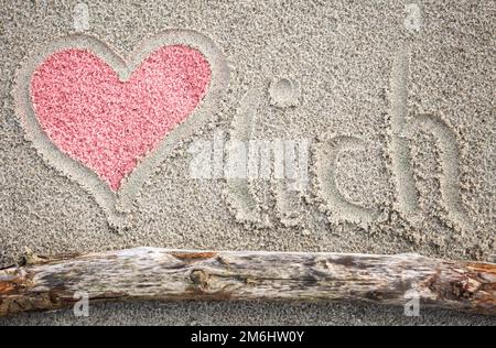 Un cuore disegnato nella sabbia, e la parola Herzlich. Foto Stock