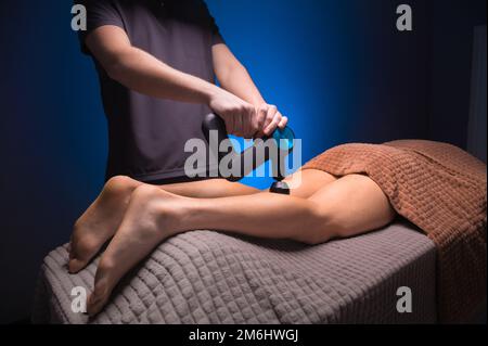 Massaggio a percussione sul dorso della gamba. Massaggiare la parte posteriore della coscia e la parte posteriore dei muscoli del polpaccio. Lavorare come percussi Foto Stock