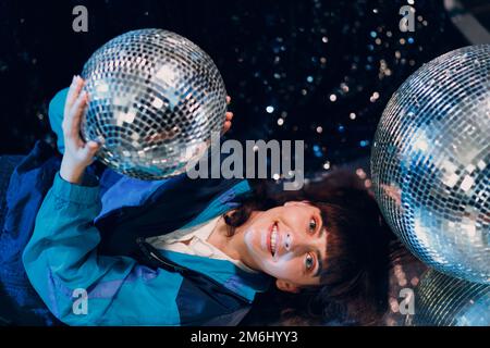 Giovane donna sportiva stile anni '80 e '90. 90s ragazza moda positiva al night club discoteca party con discoteca ball. Foto Stock