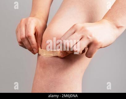 Applicazione di cerotto medico, cerotto sulla ferita del ginocchio primo piano. Foto di alta qualità Foto Stock