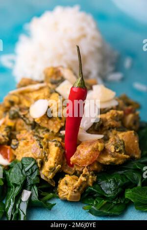 Pollo indiano murgh palak su un piatto blu Foto Stock