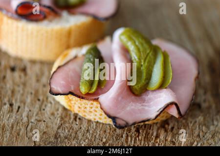 Sandwich al prosciutto con cetriolo su legno Foto Stock