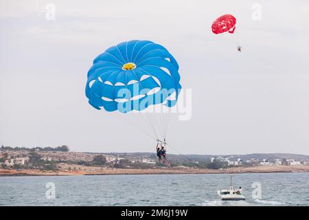 Ayia Napa, Cipro - 16 giugno 2018: Parasailing nella città di Agia Napa, motoscafo e paracadute blu con i turisti Foto Stock