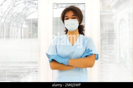 Giovane lavoratore medico afroamericano stanco sovraccaricato che indossa una maschera protettiva Foto Stock