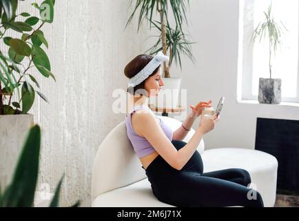 Incinta giovane donna di applicare la crema al mattino Foto Stock