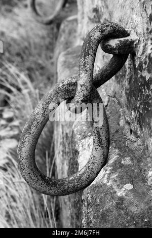 Immagini monocromatiche di vecchie maglie di catene di ferro, fissate ad un muro di pietra sulla passerella del fiume che si avvicina al centro di Dresda, Sassonia, Germania Foto Stock