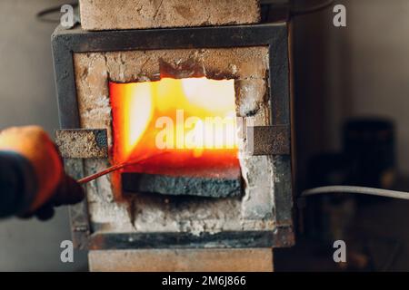 Forno di fucina con fiamma calda. Smith scaldante pezzo di acciaio in fuoco di fucina rosso-caldo Foto Stock