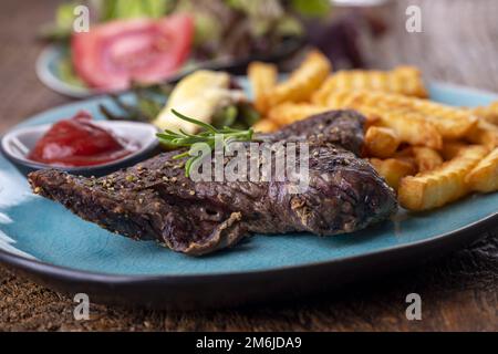 Rosmarino su una bistecca con patatine fritte Foto Stock