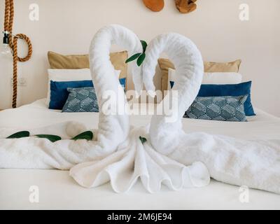 Asciugamano bianco cigni coppia bacio forma a cuore sul letto lenzuola hotel camera decorazione sfondo Foto Stock