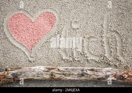 Un cuore disegnato nella sabbia, e la parola Herzlich. Foto Stock
