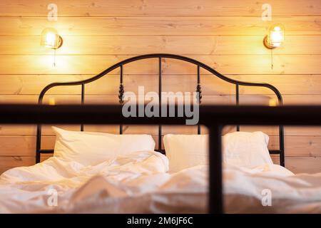 Camera da letto in casa di legno hotel.Letto con comodo cuscino, vero appartamento.Inverno bianco luminoso cottage elegante design Foto Stock