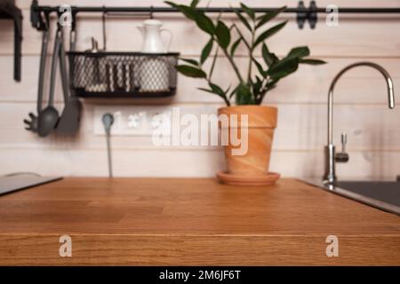 Utensili da cucina in ottone, accessori per chef. Cucina appesa con muro di piastrelle bianche e pianta in legno tabletop.Green sul retro della cucina Foto Stock