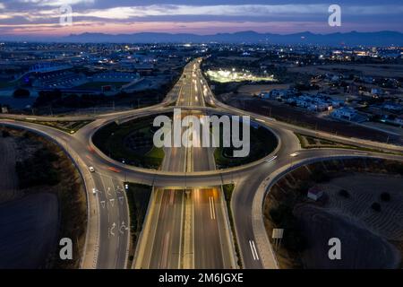 Vista aerea del drone dello svincolo autostradale. Le macchine rotatorie si muovono velocemente. Infrastrutture di trasporto Foto Stock