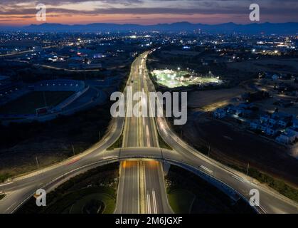 Vista aerea del drone dello svincolo autostradale. Le macchine rotatorie si muovono velocemente. Infrastrutture di trasporto Foto Stock