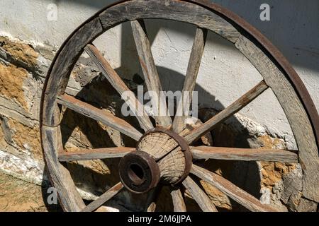 Vecchia ruota di legno del carro di paese come decorazione della parete della casa rurale Foto Stock