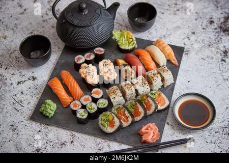 Assortimento di tipi differenti di sushi rotoli posti sulla pietra nera board Foto Stock