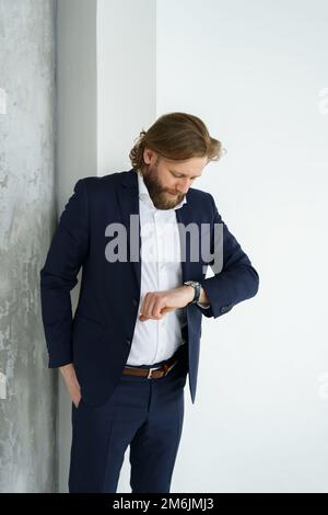 Un bel brutale uomo bearded e a capelli lunghi, un uomo d'affari elegante su uno sfondo bianco Foto Stock
