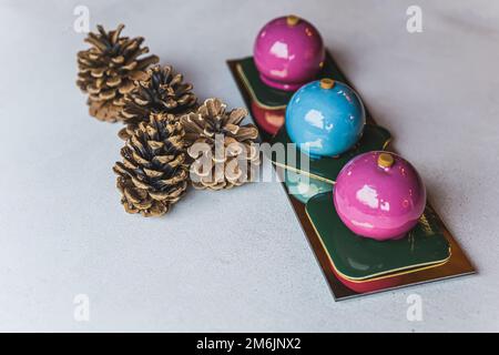 Vista frontale di due torte rosa e una blu poste in linea su un piatto rettangolare dorato. Quattro coni posti accanto alla piastra. Sfondo sfocato. Foto di alta qualità Foto Stock