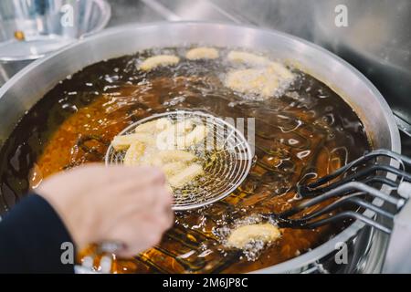 Preparazione di churros fritti con zucchero tipico della Spagna Foto Stock