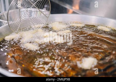 Preparazione di churros fritti con zucchero tipico della Spagna Foto Stock