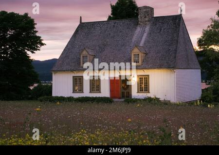 Vecchia casa in stile cottage del regime francese del 1752 illuminata al tramonto in estate, Saint-Francois, Ile d'Orleans, Quebec, Canada. Foto Stock