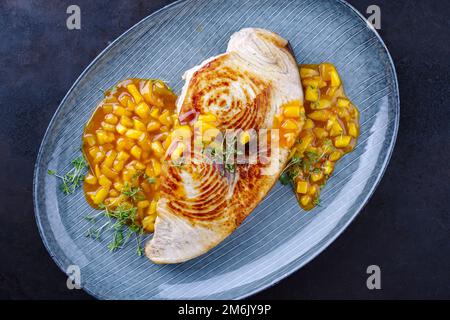 Bistecca di pesce spada fritto con chutney di mango ed erbe servite come vista dall'alto su un piatto di design Foto Stock