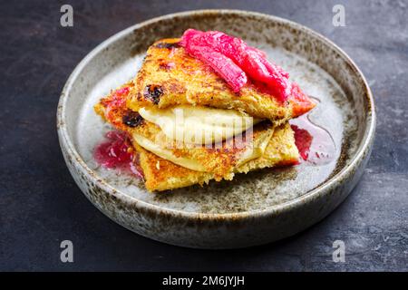 Tiramisù panettone tradizionale italiano arrosto con crema alla vaniglia cagliata e rabarbaro servito come primo piano in una ciotola dal design nordico Foto Stock